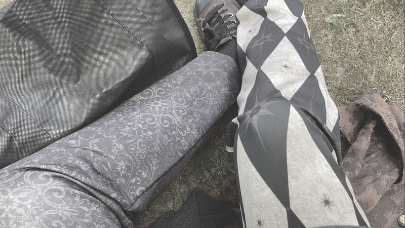 photo of perspective looking down sitting on a jacket on grassy ground next to a black tote. the pants are split-leg - one with a diamond pattern and one with a filagree pattern
