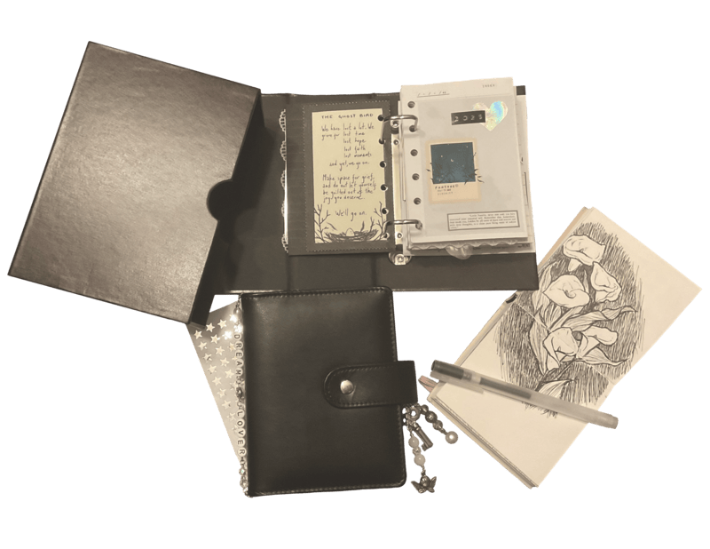 photo with transparent background of stationery including a black pocket ring binder with charms, an open archival binder and sleeve, and small sketchbook showing a sketch of calla lilies