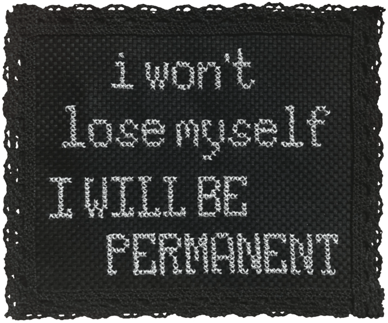a photo of a silver-threaded cross-stitch on black aida cloth. it reads "i won't lose myself / i will be permanent" with the second phrase in capital letters